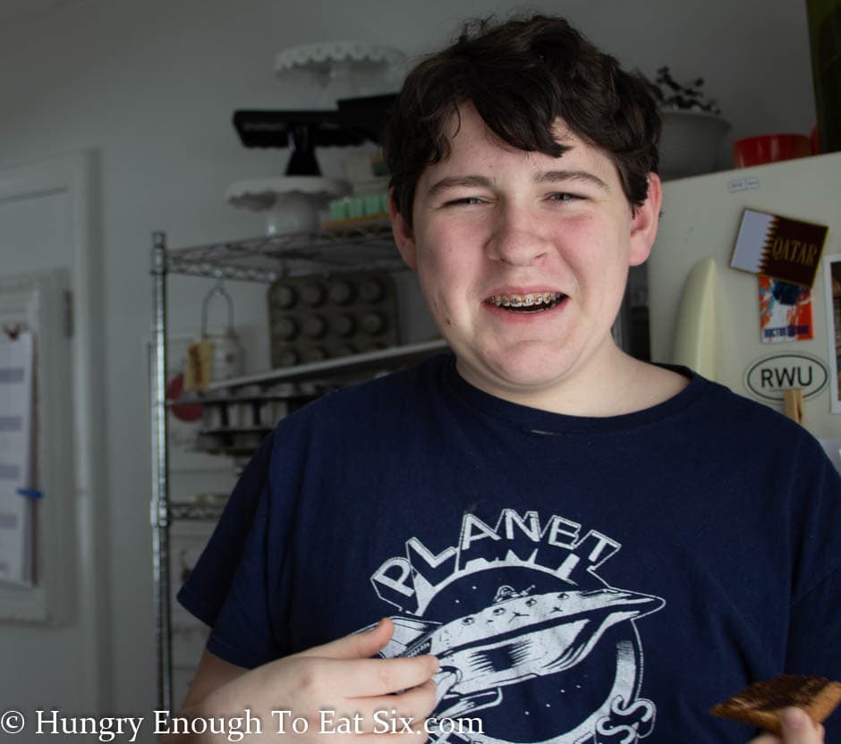 Teen boy making face when trying toast.