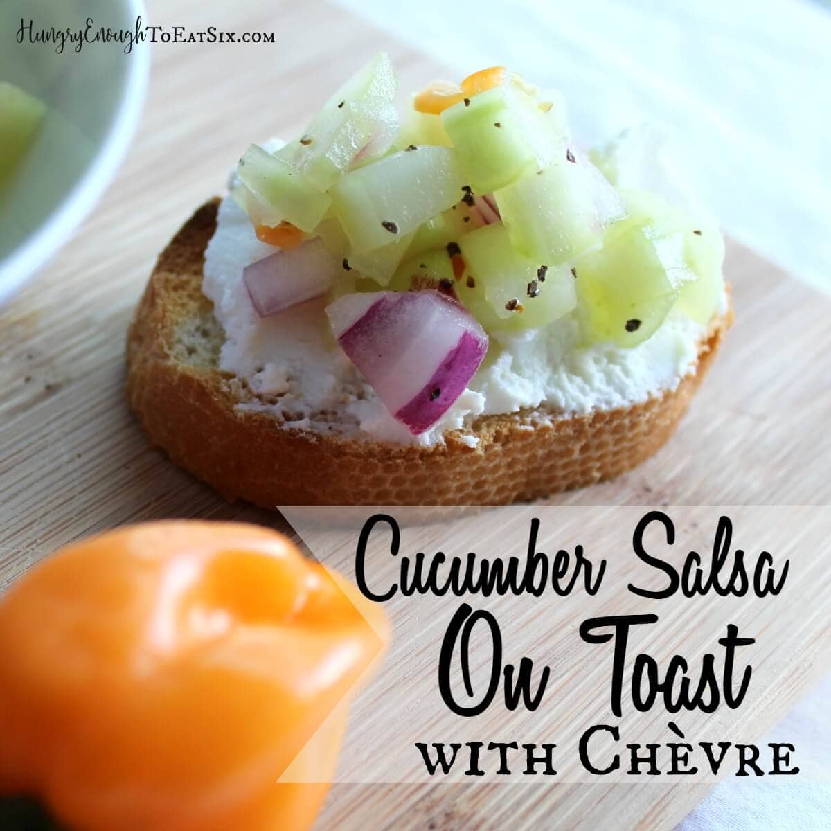 Vertical image of cucumber salsa-topped chevre toast on a cutting board, next to a pepper. With text overlay