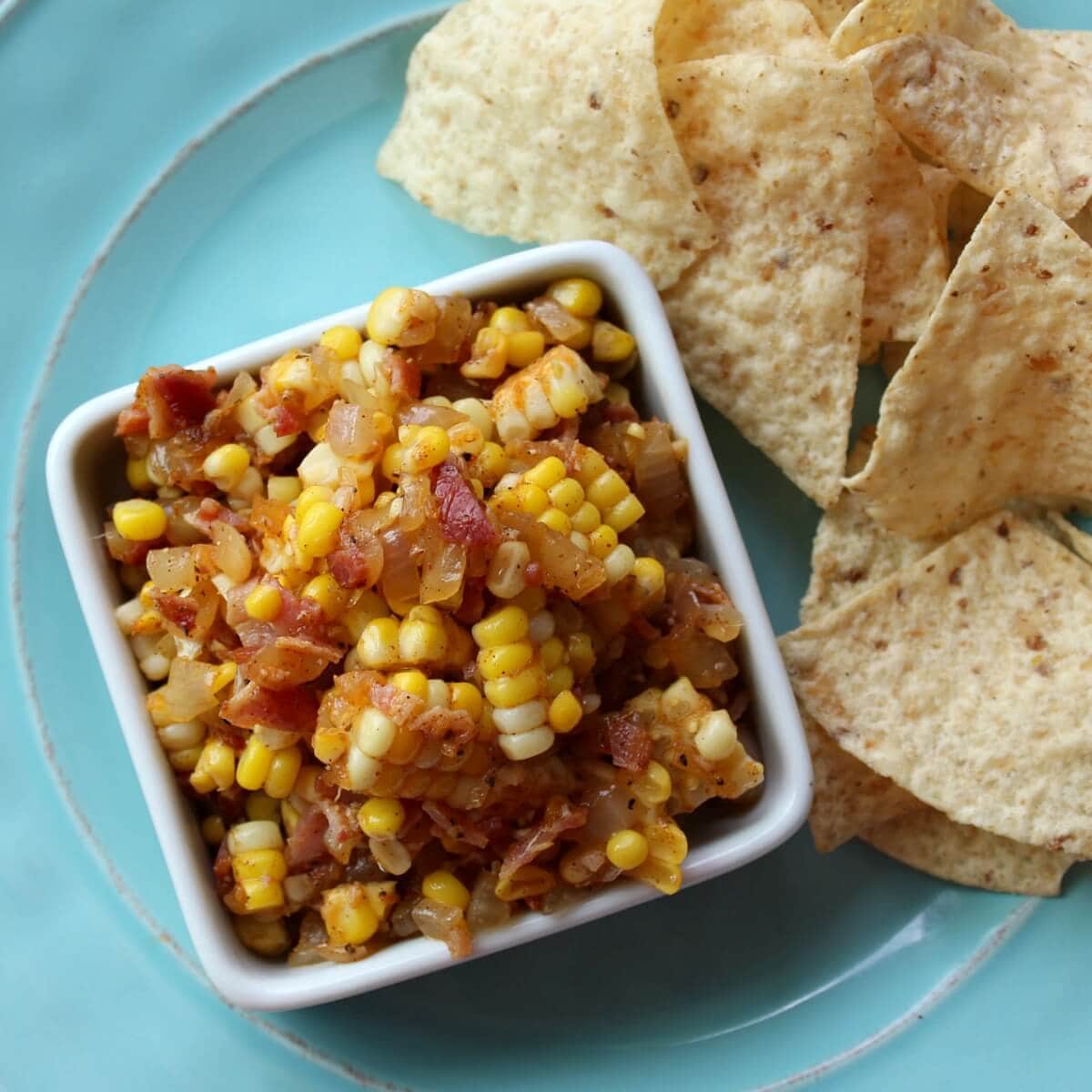 Image of Corn, Vidalia Onion and Bacon Salsa in a square dish with tortilla chips.