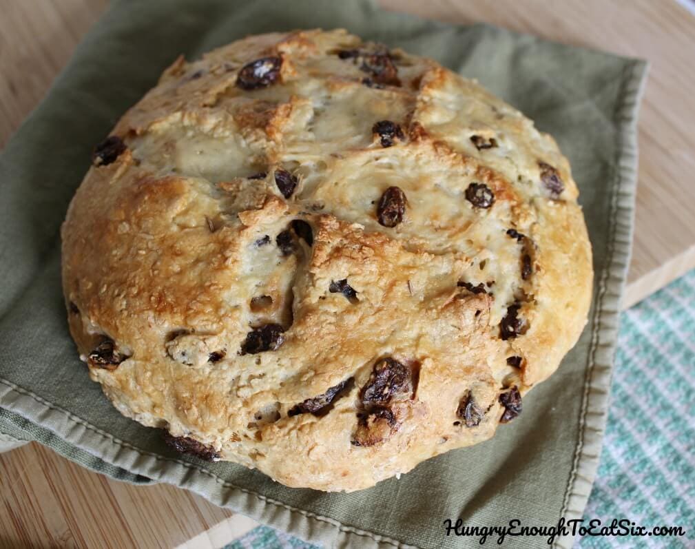 Image of baked, browned loaf of Irish Soda Bread studded with raisins.