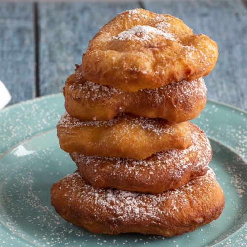 Five fried bread dough pieces stacked on a plate