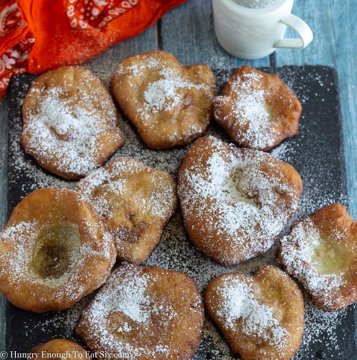 Black slate board with fried dough and all dusted with powdered sugar