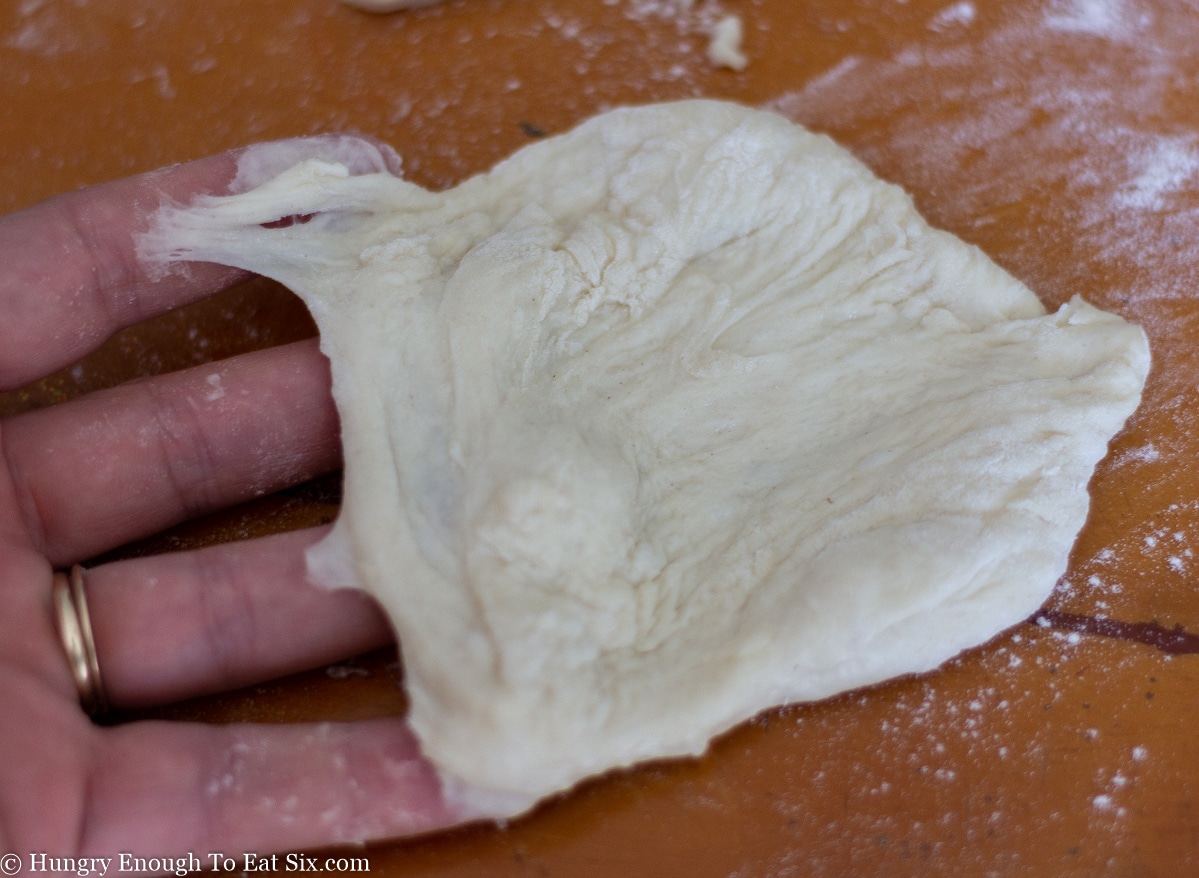 Piece of bread dough stretched over fingers.