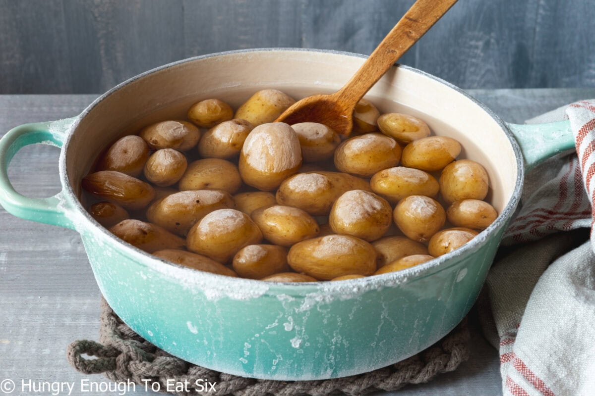 Cooked potatoes in water with salt crusted on the outside.