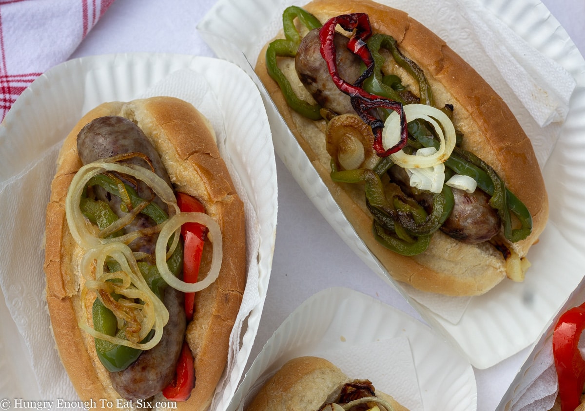 Two sausage pepper and onion rolls on paper plates,
