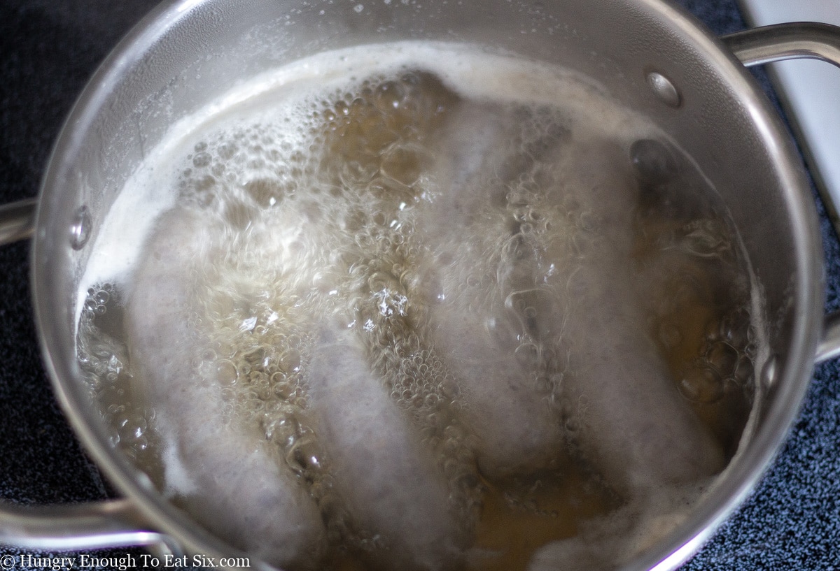 Sausages simmering in a saucepan in beer.