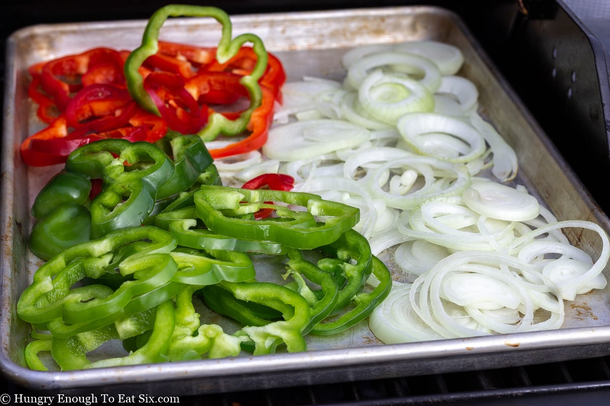 Fresh slices of bell peppers and onions on baking sheet