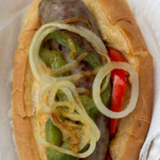 Sandwich roll with sausage, sliced peppers and onions