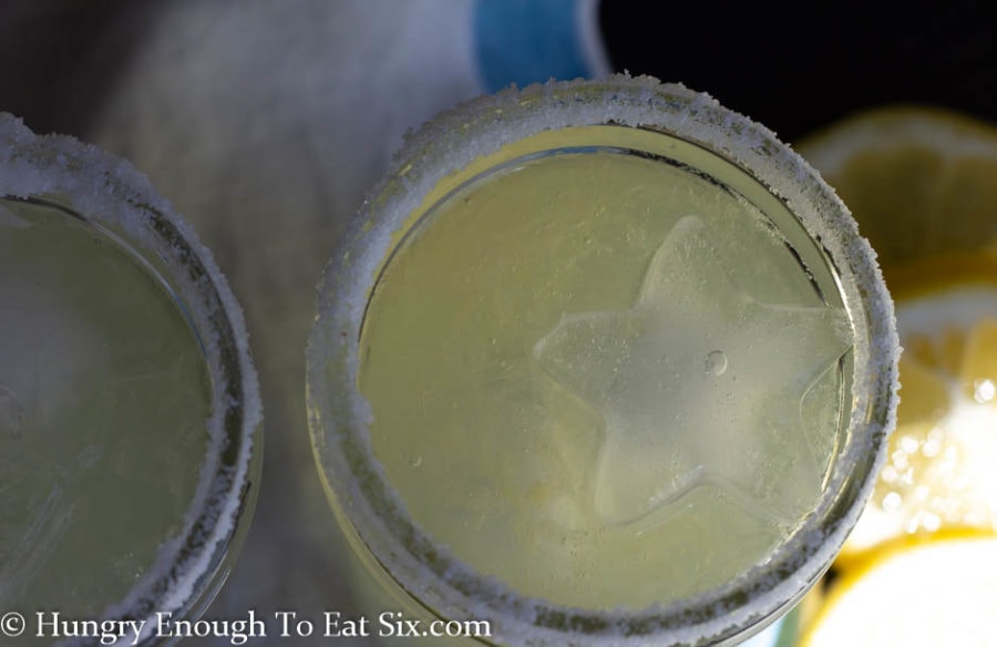 Close-up of a small mason jar with salted rim and margarita with ice inside.