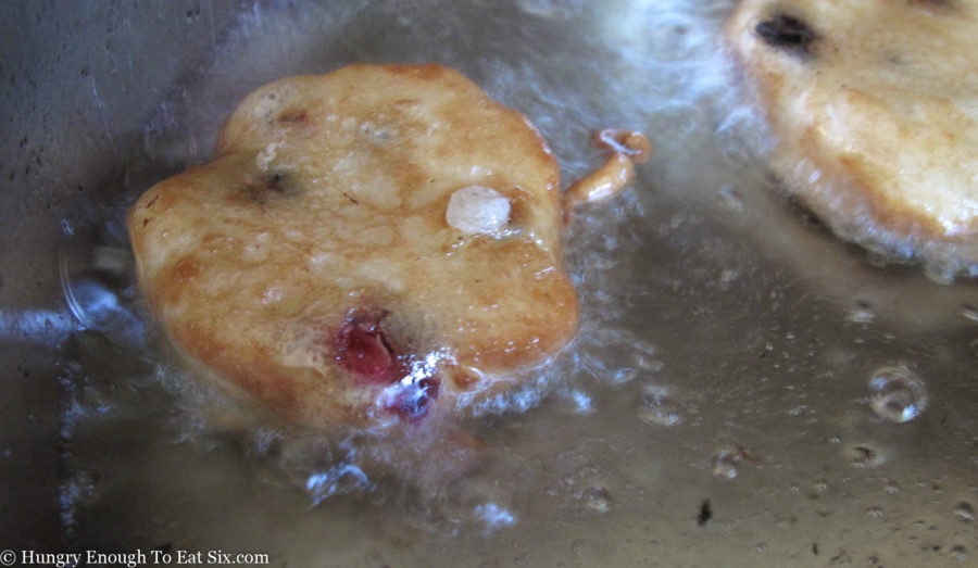 Blueberry fritter frying in oil.
