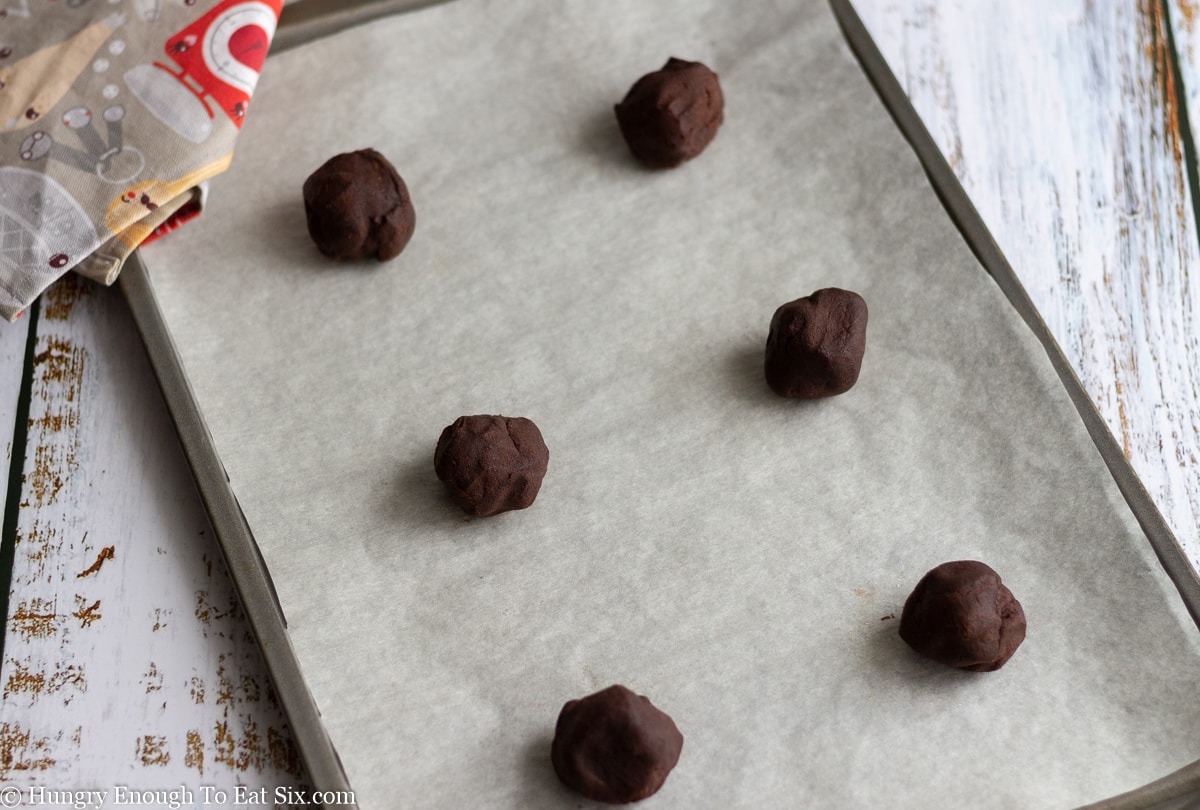 Balls of chocolate cookie dough on a baking sheet