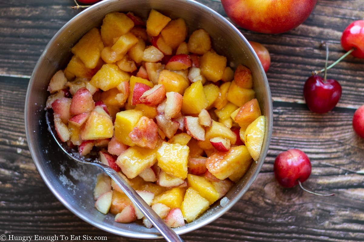 Chopped nectarines and chopped cherries in a silver bowl.
