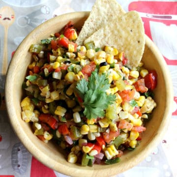 Small bowl of corn and veggie salsa with tortilla chips.
