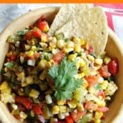 Corn and veggies salsa in a wood bowl with tortilla chips.