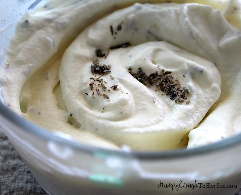 Homemade whipped cream in a glass bowl with lavender buds swirled through.