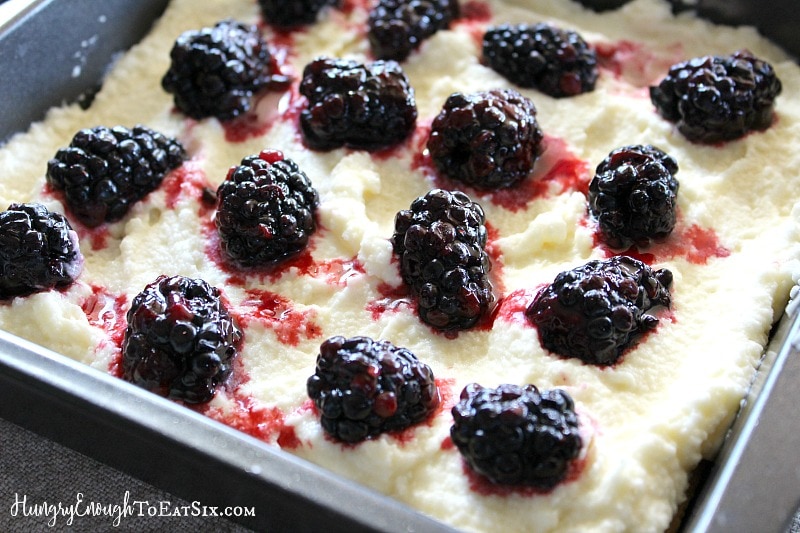 Square pan holding mascarpone cheese and topped with blackberries.