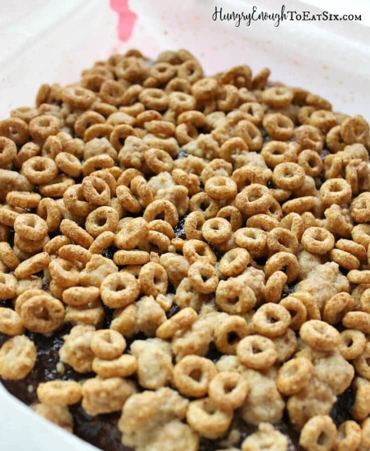 Long pan with cheerios spread over a dark fruit filling