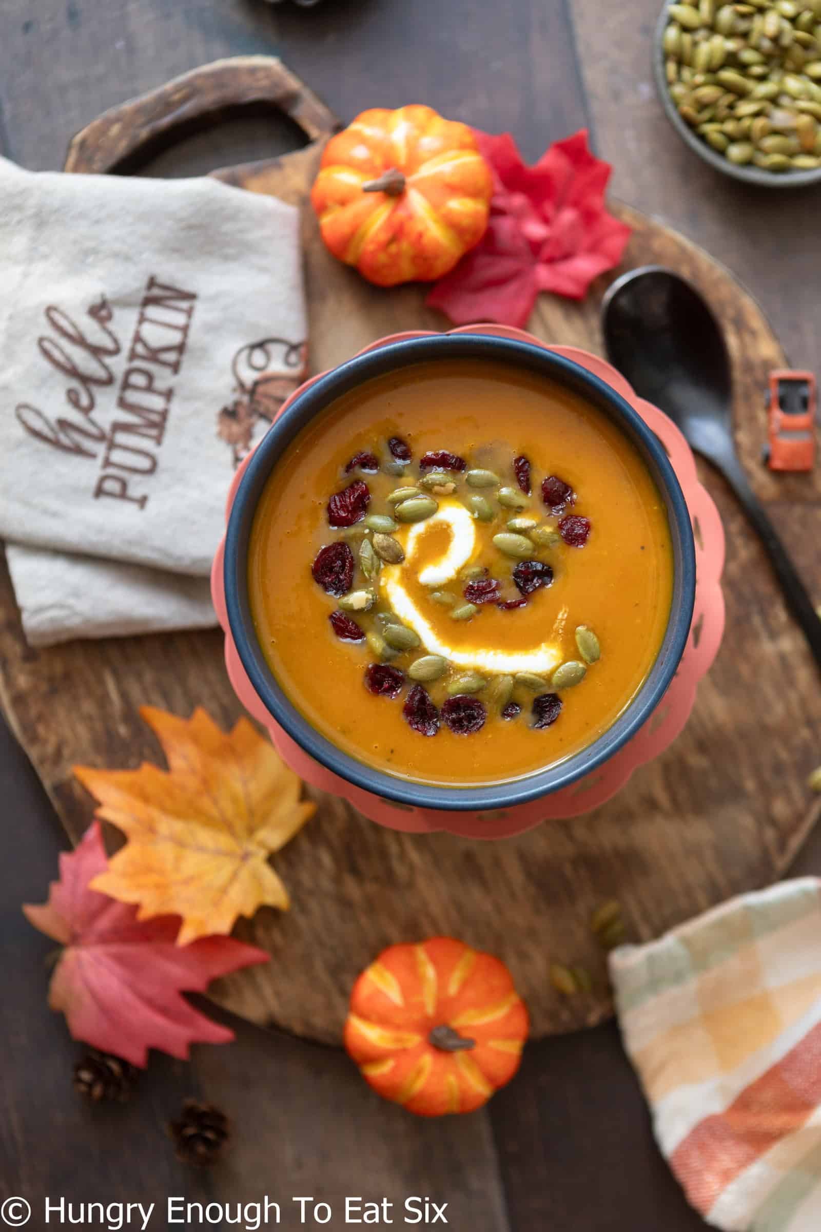 Bowl of spicy pumpkin soup with pepitas and cranberries.
