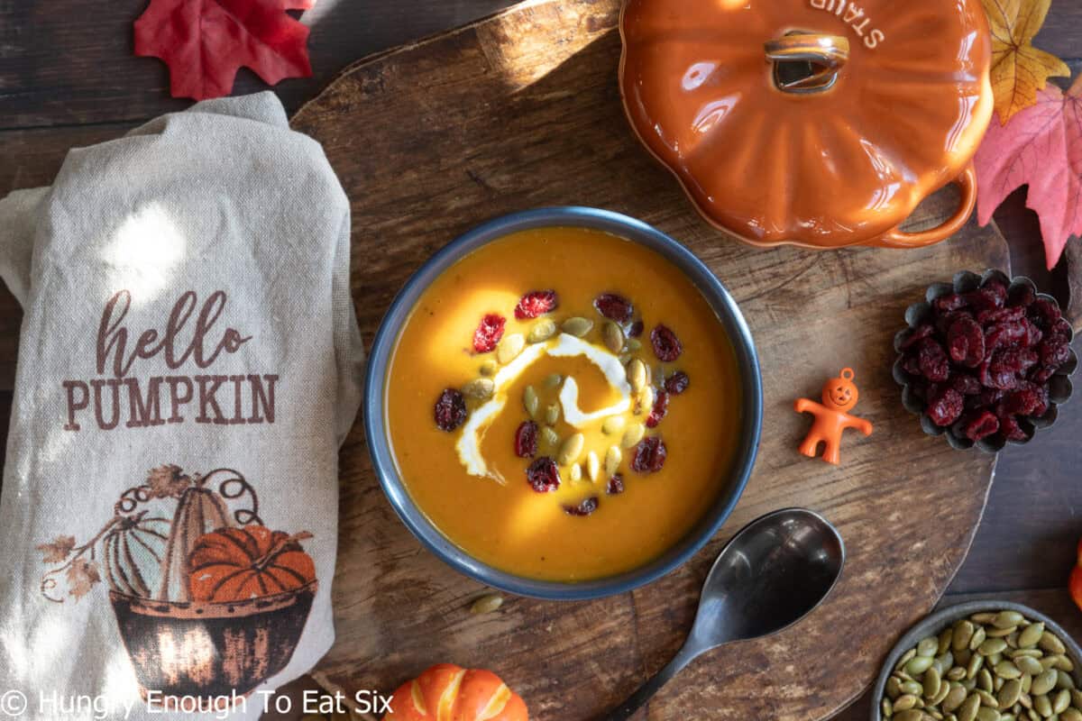 Sunlight on a bowl of spicy pumpkin soup with toppings.