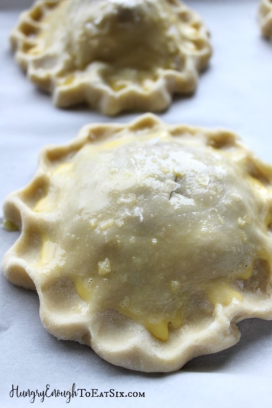Unbaked hand pies with pastry crust brushed with egg yolk