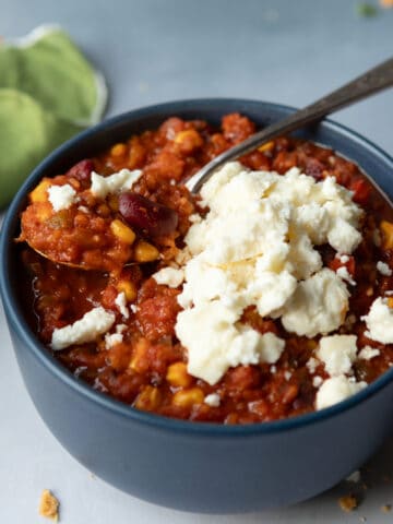 Chili in a bowl topped with cheese crumbles.