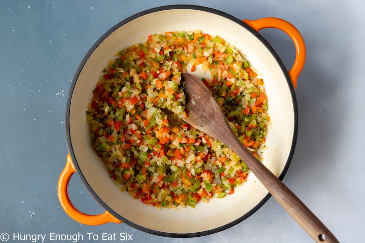 Pot with diced veggies and wooden spoon inside.