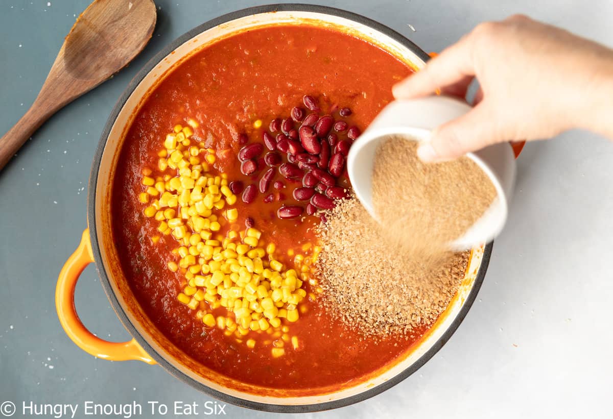 Yellow stock pot with red sauce, corn, beans, and bulgur.
