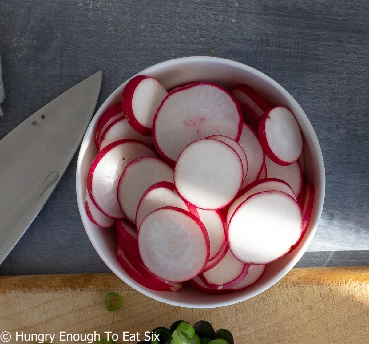 Bowl of round slices of red and white radishes.