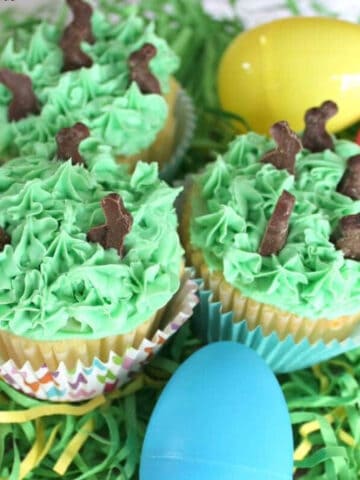 Cupcakes with green frosting and chocolate bunnies.