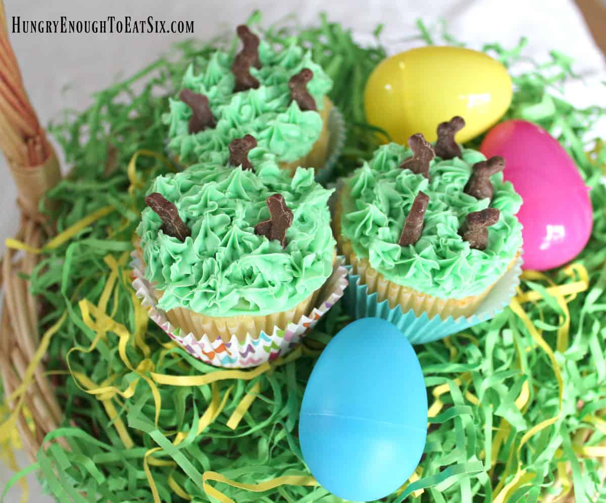 Green frosted cupcakes with tiny chocolate rabbits and plastic Easter eggs.