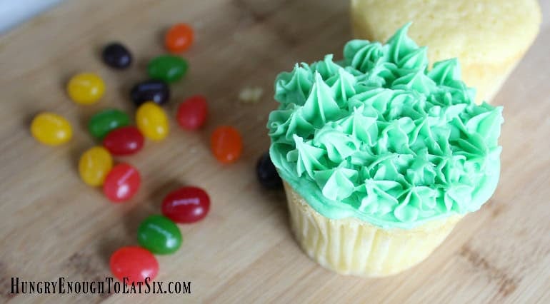Cupcake with tufts of green frosting to look like grass for Easter Surprise Cupcakes.