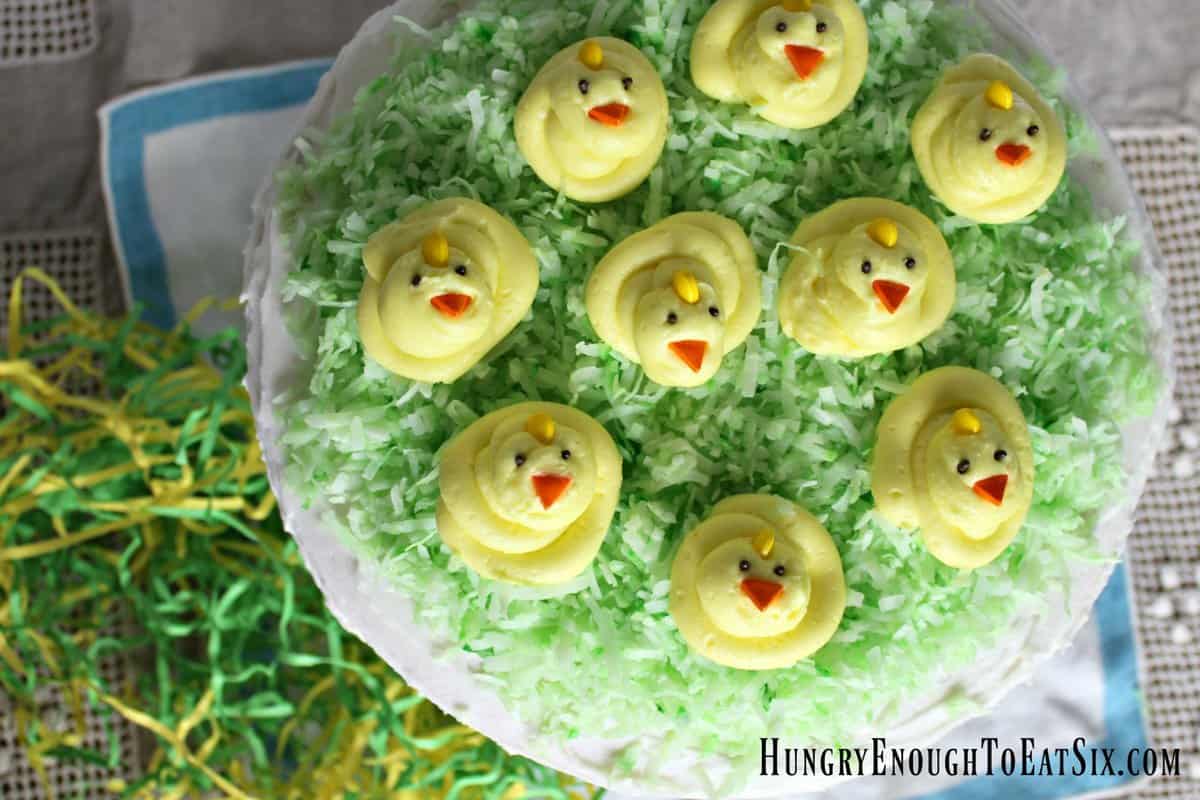 Round frosted cake with several yellow buttercream chicks.