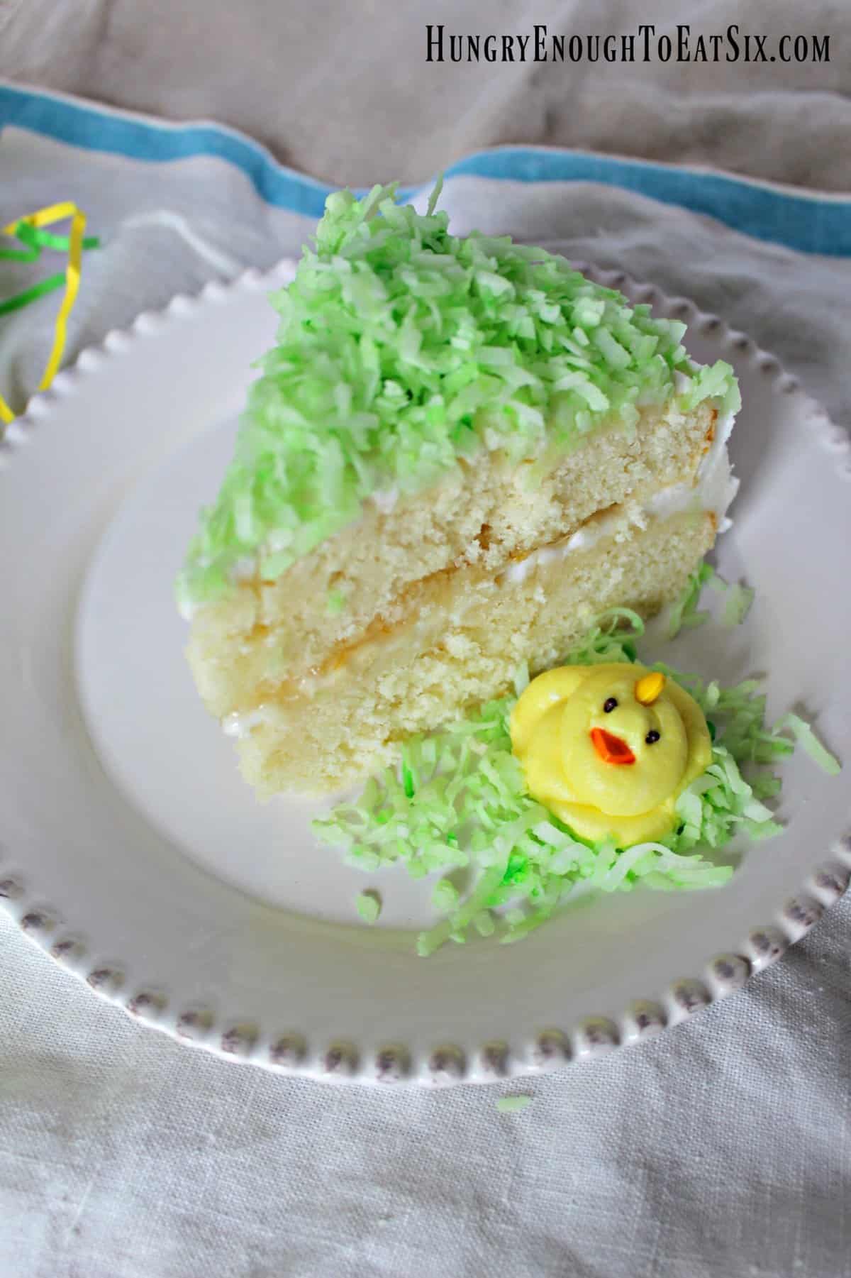 Slice of white layer cake with green coconut on top.