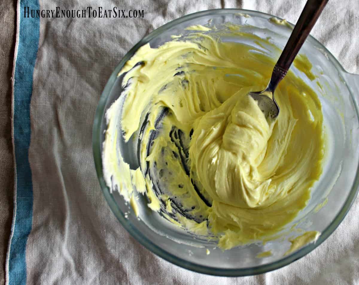Yellow-tinted buttercream frosting in bowl.