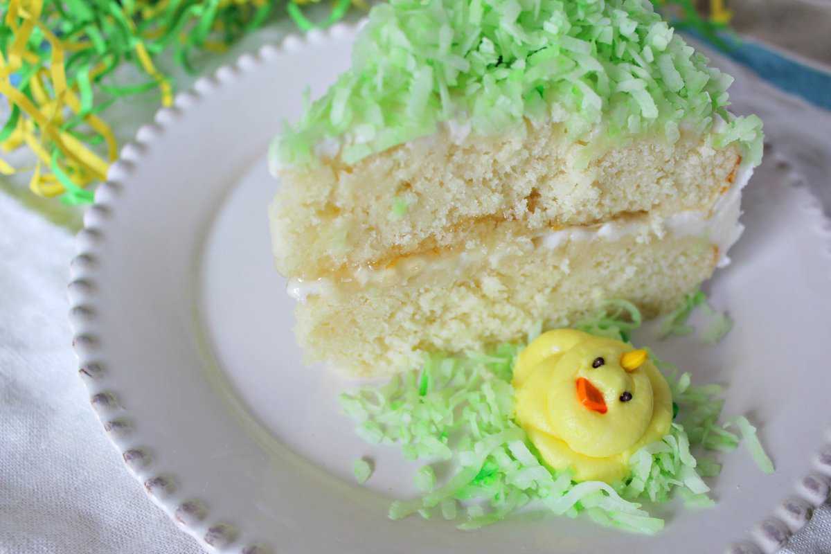 Slice of layer cake with green coconut and yellow frosting chick.