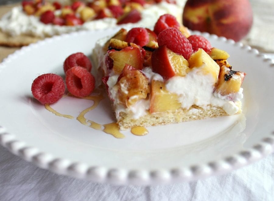 White plate with a shortcake slice topped with peaches