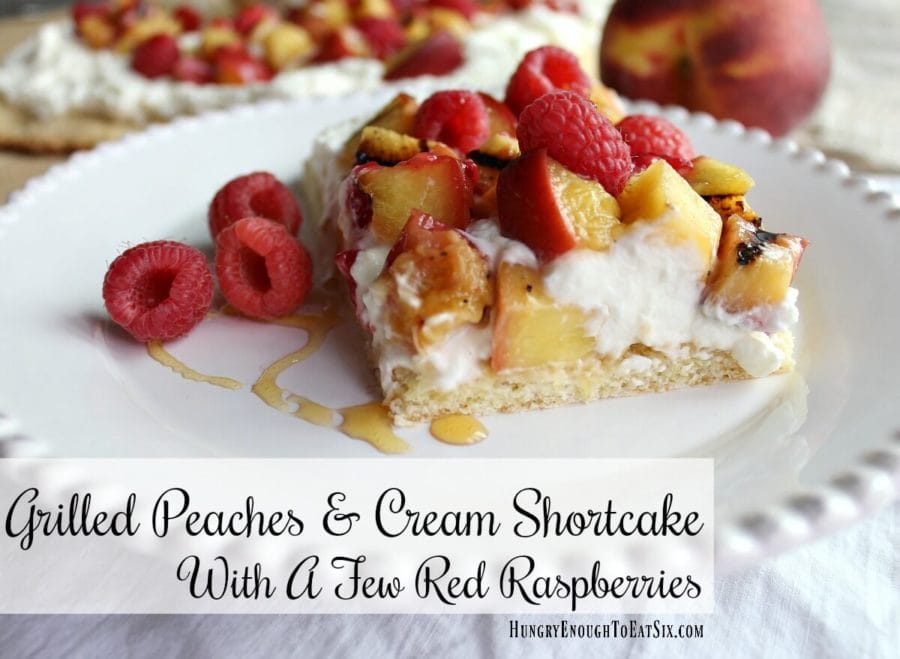 Peaches and cream shortcake with rapsberries and a drizzle of honey on a white plate.