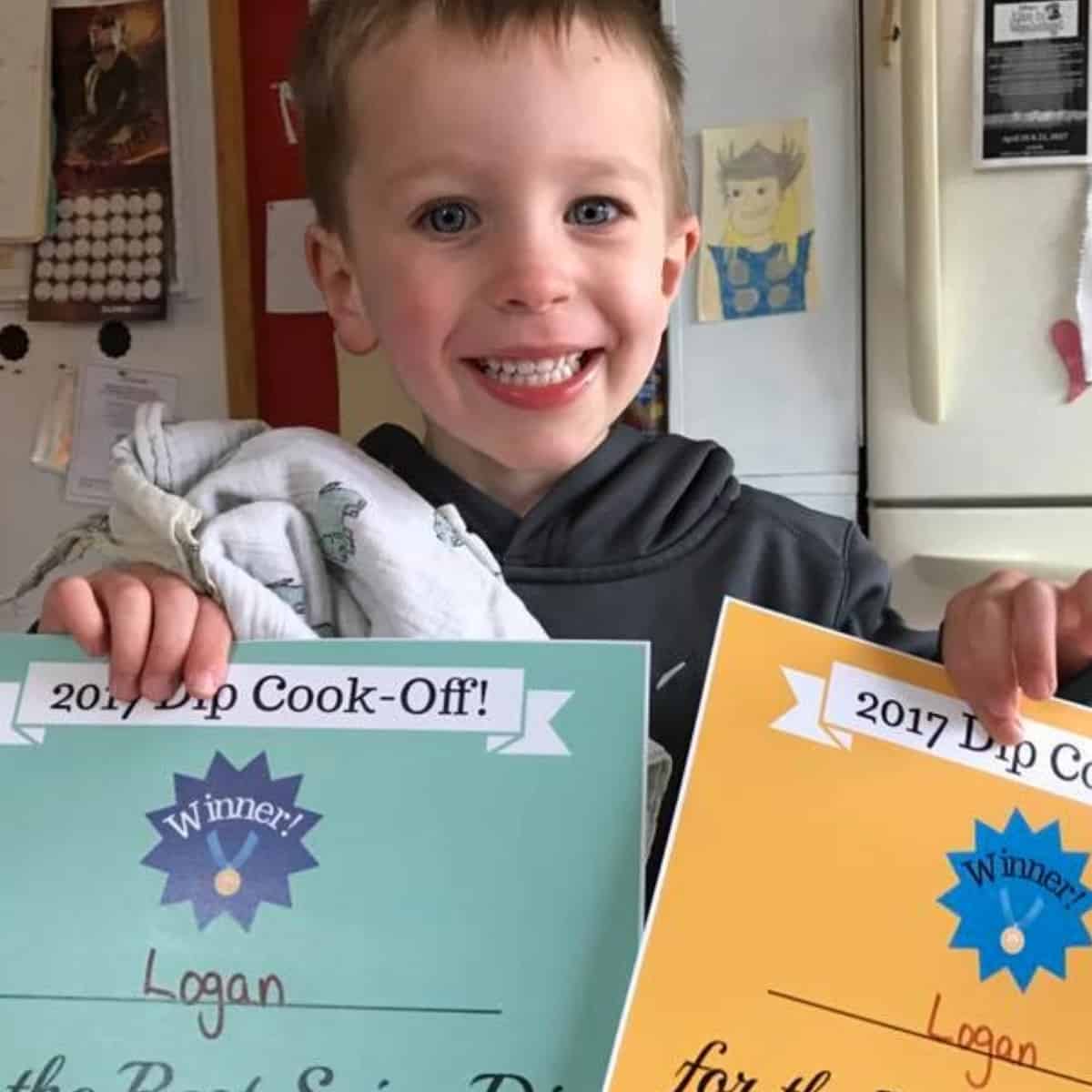 Little boy holding two certificates.