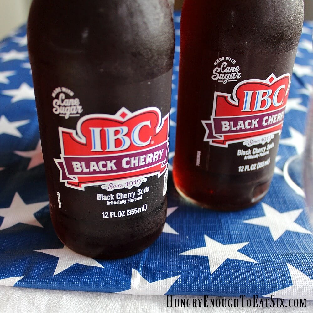 Two bottles of IBC Black Cherry Soda on blue tablecloth printed with white stars.