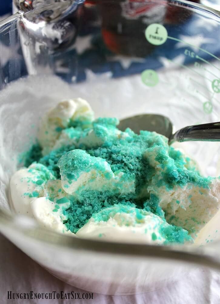 Vanilla ice cream topped with blue Pop Rocks candies in a clear bowl.