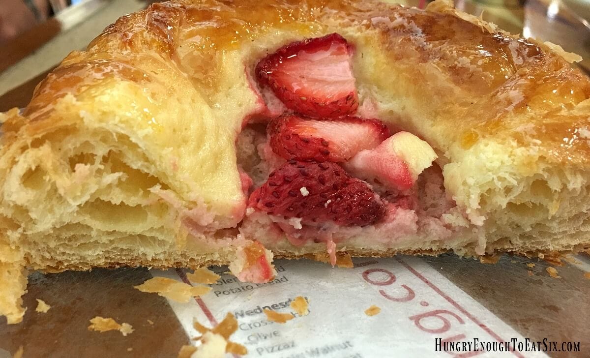 Pastry cut in half to show flaky layers and the strawberry filling in the center. 