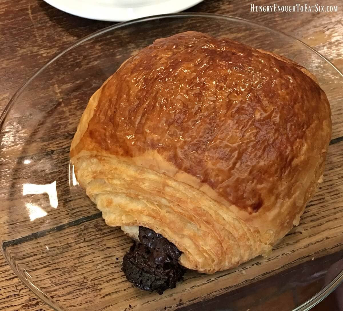A chocolate-filled croissant with lots of flaky layers and a shiny top.