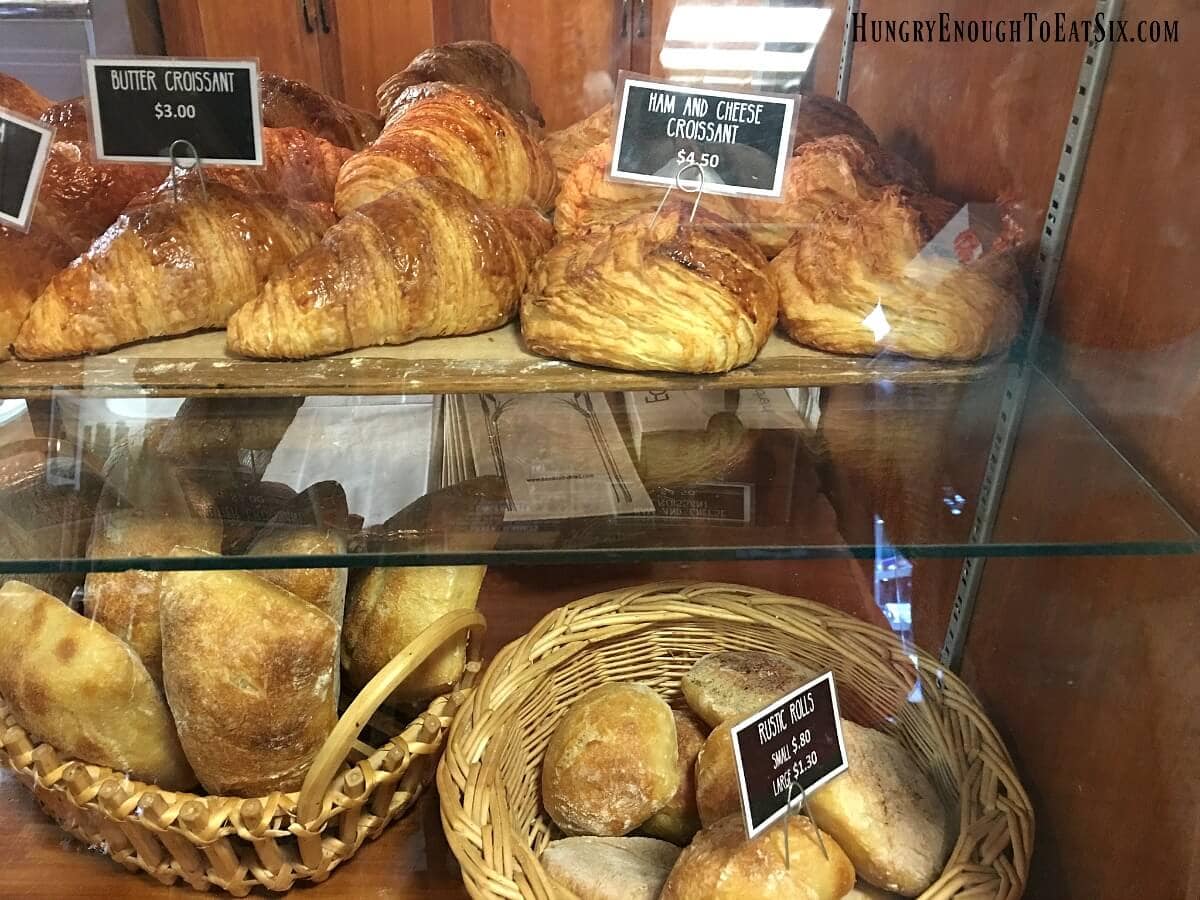 Croissants and rolls in baskets inside a bakery case. 