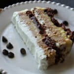 Slice of chocolate, peanut butter and whipped cream icebox cake on white plate.