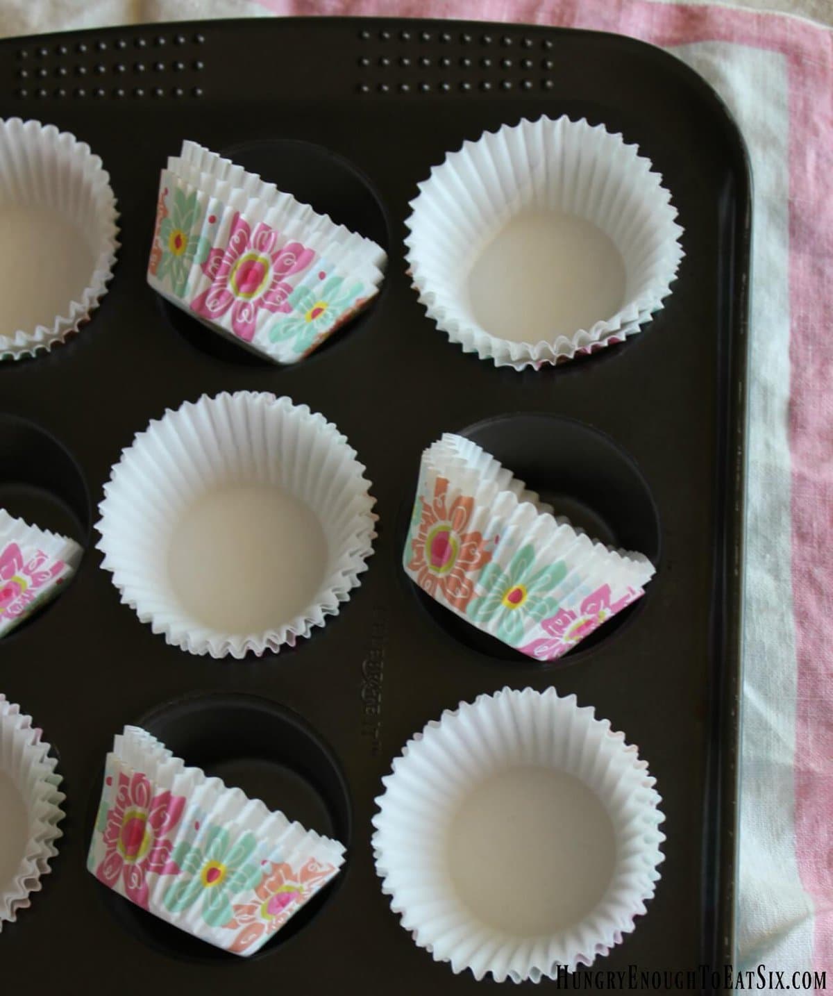 Mini muffin pan with white and floral paper lines in the cups.
