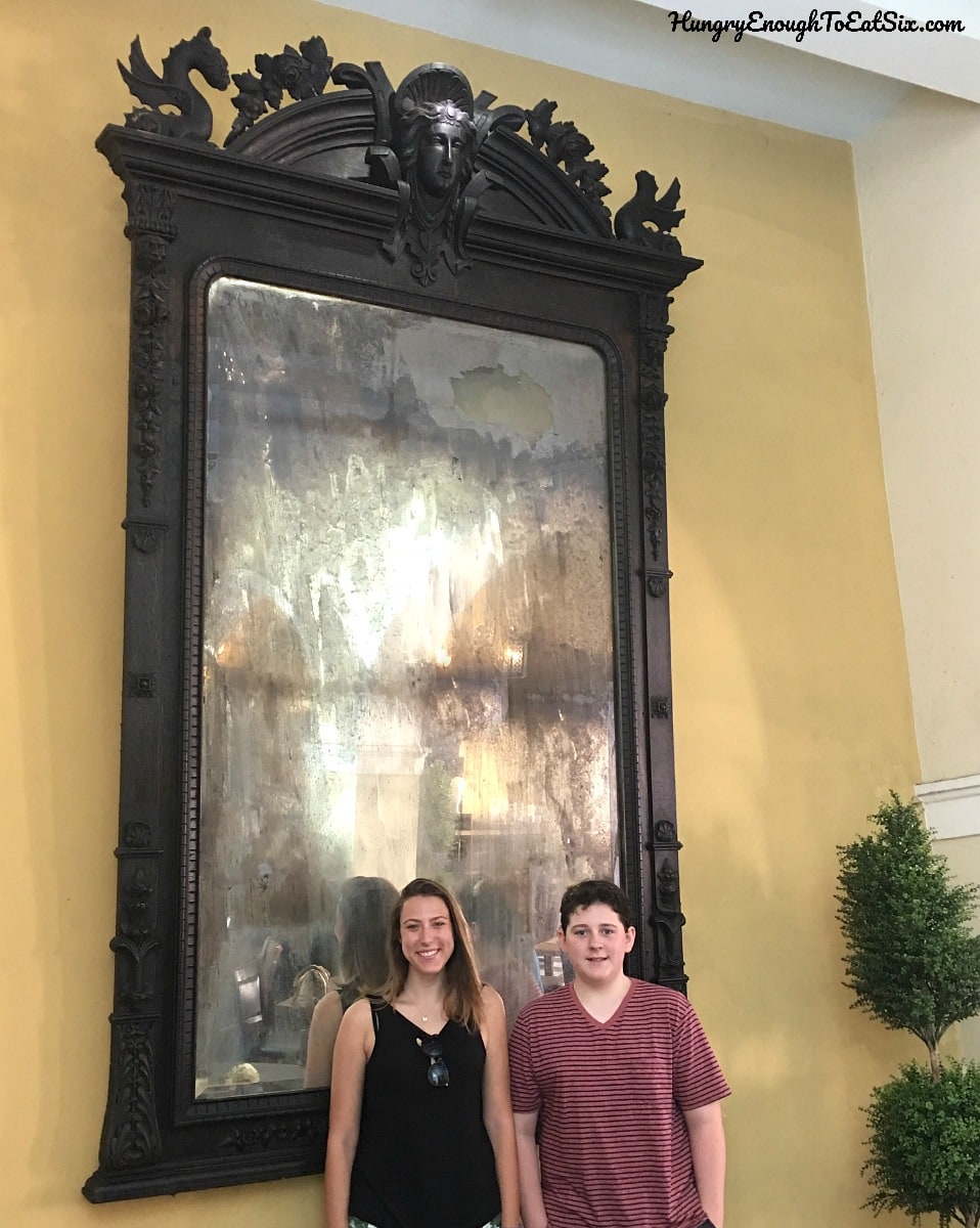 Tall antique mirror behind two teens