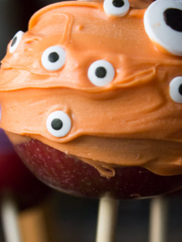 Orange coated apple with candy eyes, on a wood stick