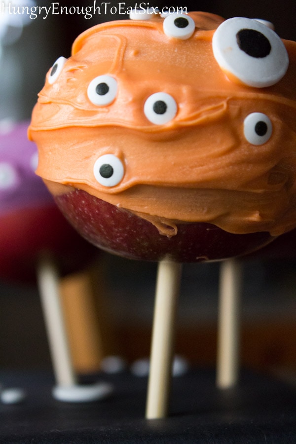 Apples on wooden stick with orange coating and eyes.