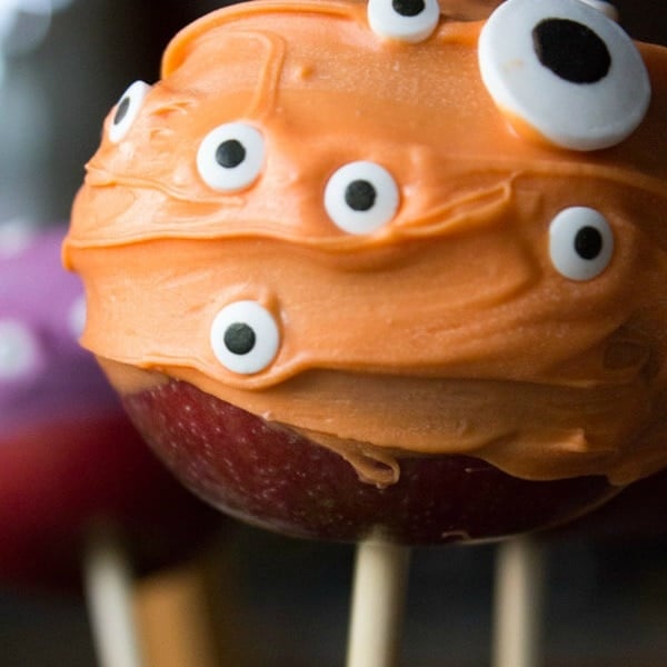 Red apple on a stick coated with orange candy and candy eyes