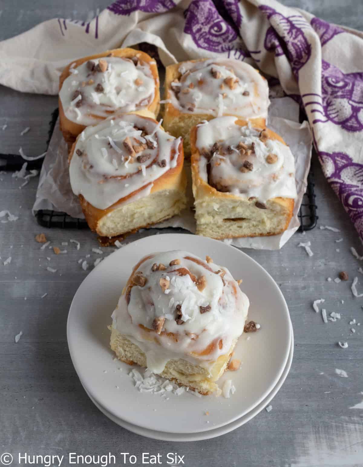 Five large sweet buns with white frosting.